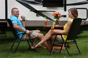 couple on camp chairs in front of 5th wheel RV