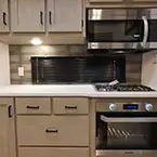 Kitchen area with microwave, stove, and lower and upper cabinets May Show Optional Features. Features and Options Subject to Change Without Notice.