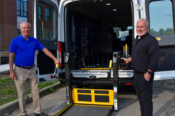 Dave Brown, General Manager of MobilityTRANS, and Fr. Tim McCabe, Executive Director of the Pope Francis Center, at the back of a Ford E-Transit.